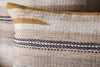 The nkuku Aravali Wool Cushion Cover - Ochre features a textured woven design with horizontal stripes and patterns in beige, cream, brown, and mustard yellow for a cozy neutral look.