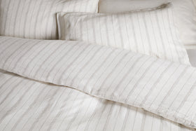 Close-up of a neatly made bed with the nkuku Anta Hemp & Cotton Duvet Cover in sage green, featuring breathable fabric for a clean and cozy look.