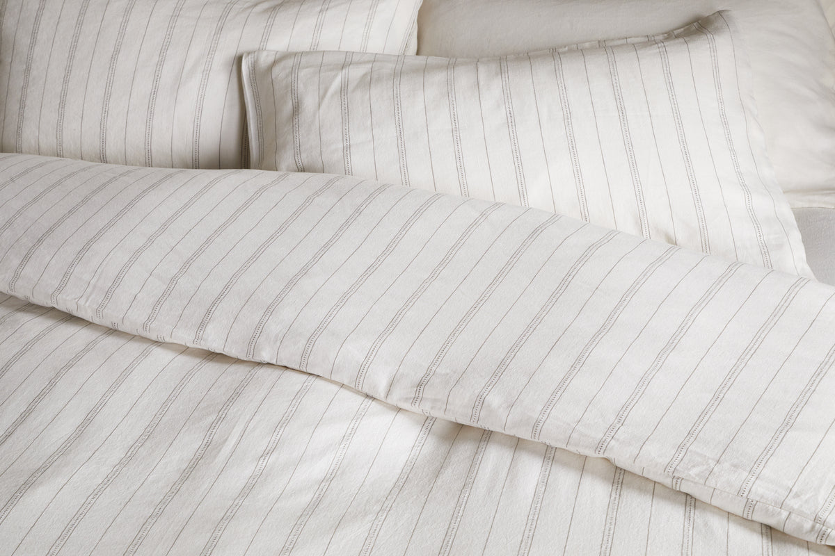 Close-up of a neatly made bed with the nkuku Anta Hemp & Cotton Duvet Cover in sage green, featuring breathable fabric for a clean and cozy look.