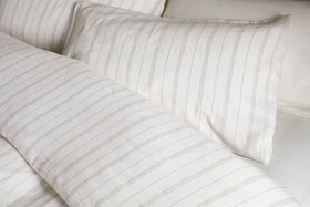 Close-up of a neatly made bed with the nkuku Anta Hemp & Cotton Duvet Cover in sage green, paired with matching pillow and sheet for a fresh, airy look. Bedding features breathable hemp-cotton blend for comfort and style.