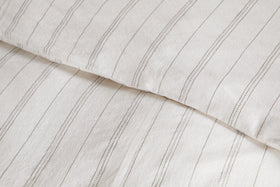 Close-up of breathable bedding with thin, vertical black stripes and a slightly wrinkled texture. Pictured is a pillow and the Anta Hemp & Cotton Duvet Cover in soothing sage green by nkuku.