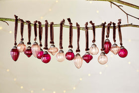The nkuku Adisa Bauble Jar - Ruby & Copper (Set of 16) brings festive charm to any branch with its mini baubles.