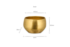 The Atsu Brass Planter by nkuku is a small, round planter with a wide opening, measuring 13.5 cm across the top, 15 cm at its widest point, and 16 cm high on the left or 10.5 cm high on the right—ideal for house plants.