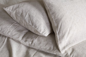 Two pillows in nkukus Borba Hemp & Cotton Housewife Pillowcases in Espresso are neatly arranged on a bed, creating a soft and cozy look.