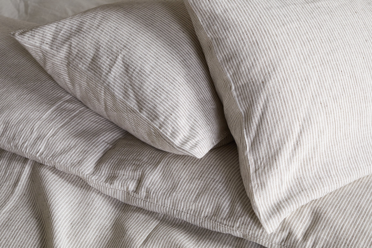 Two pillows in nkukus Borba Hemp & Cotton Housewife Pillowcases in Espresso are neatly arranged on a bed, creating a soft and cozy look.
