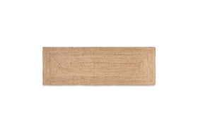 The nkuku Braided Hemp Floor Runner is a rectangular, eco-friendly mat in light tan with a simple woven texture and subtle bordered design, shown on a white background.