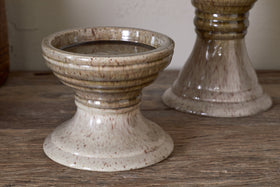 The Cabra Reactive Glaze Candle Holder by nkuku in Olive & Natural adds a unique touch to rustic decor with its distinctive design.