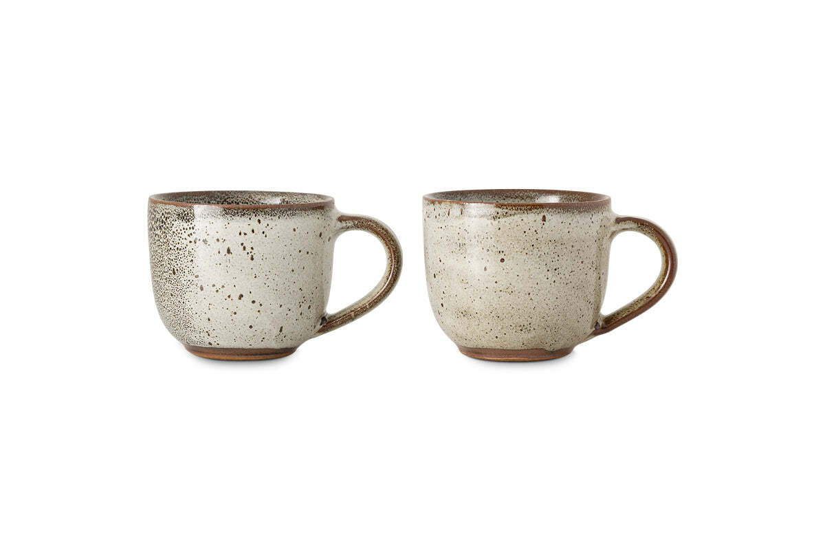 The nkuku Cam Coffee Mug - Mocha (Set of 2) features rustic mugs with handles, reactive speckled beige glaze, brownish rims, textured patterns, slightly rounded shapes, and warm brown unglazed bases displayed side by side on white.