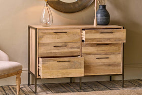 The Dasai Mango Wood Chest of Drawers by nkuku features warm mango wood, dark metal legs, and two columns of drawers—three per side, with the top two on the right open—offering a perfect blend of style and storage.
