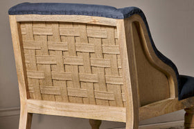 A close-up of the Elbu Deconstructed Linen Armchair by nkuku highlights its light mango wood, exposed woven burlap back, and charcoal linen fabric along the edges and seat—showcasing rustic charm with a modern twist.