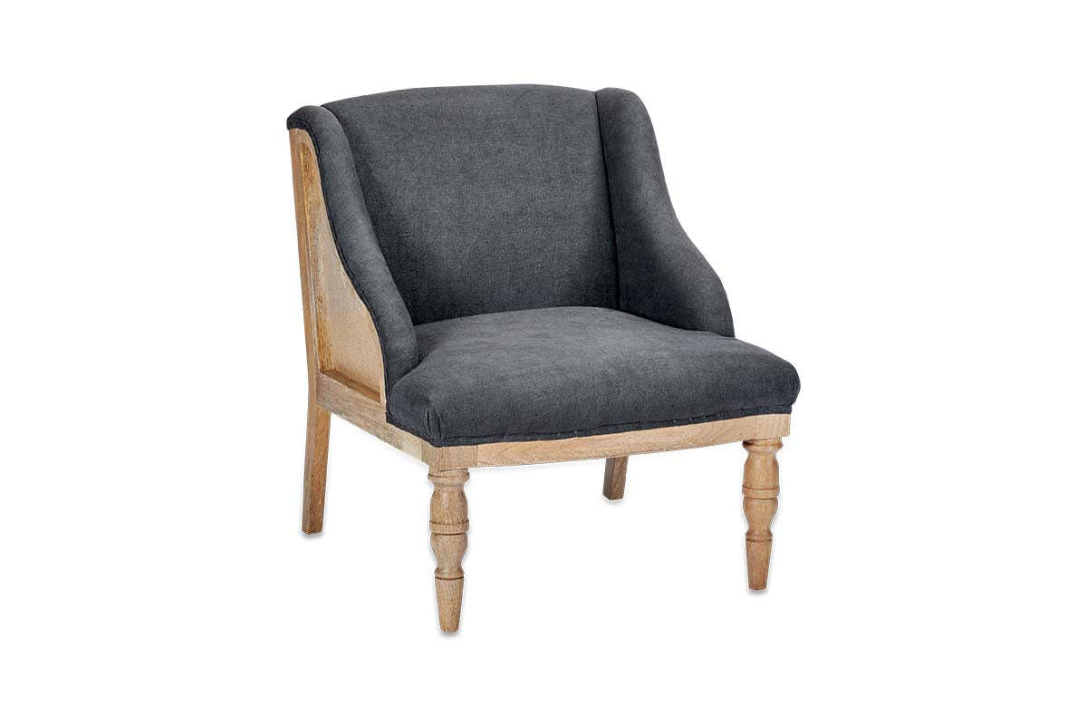 The Elbu Deconstructed Linen Armchair by nkuku features a curved backrest, armrests, and dark charcoal linen upholstery. Its light mango wood legs have carved detailing in front and simple back legs. Shown on a white background.