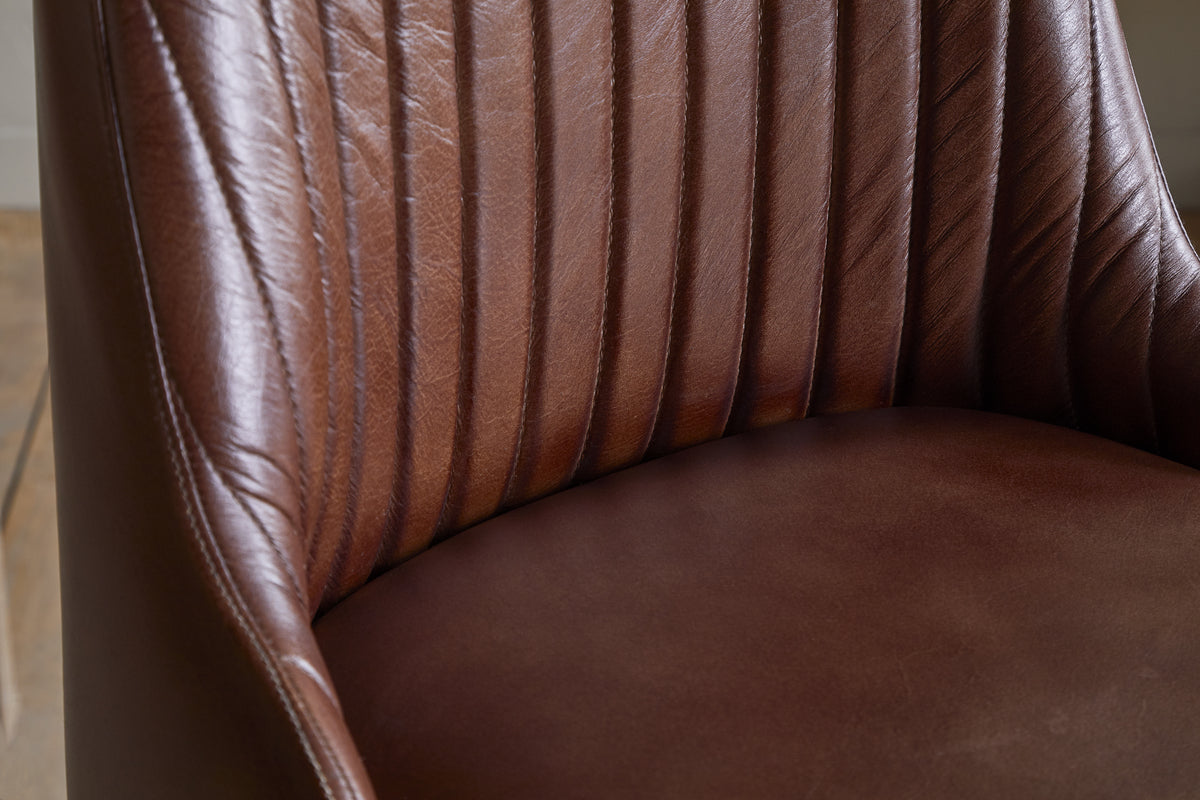 Close-up of the Harsha Leather Counter Chair by nkuku in chocolate brown, featuring vertical stitching and a smooth seat—ideal for kitchen island seating and showcasing the rich texture and sheen of its leather finish.