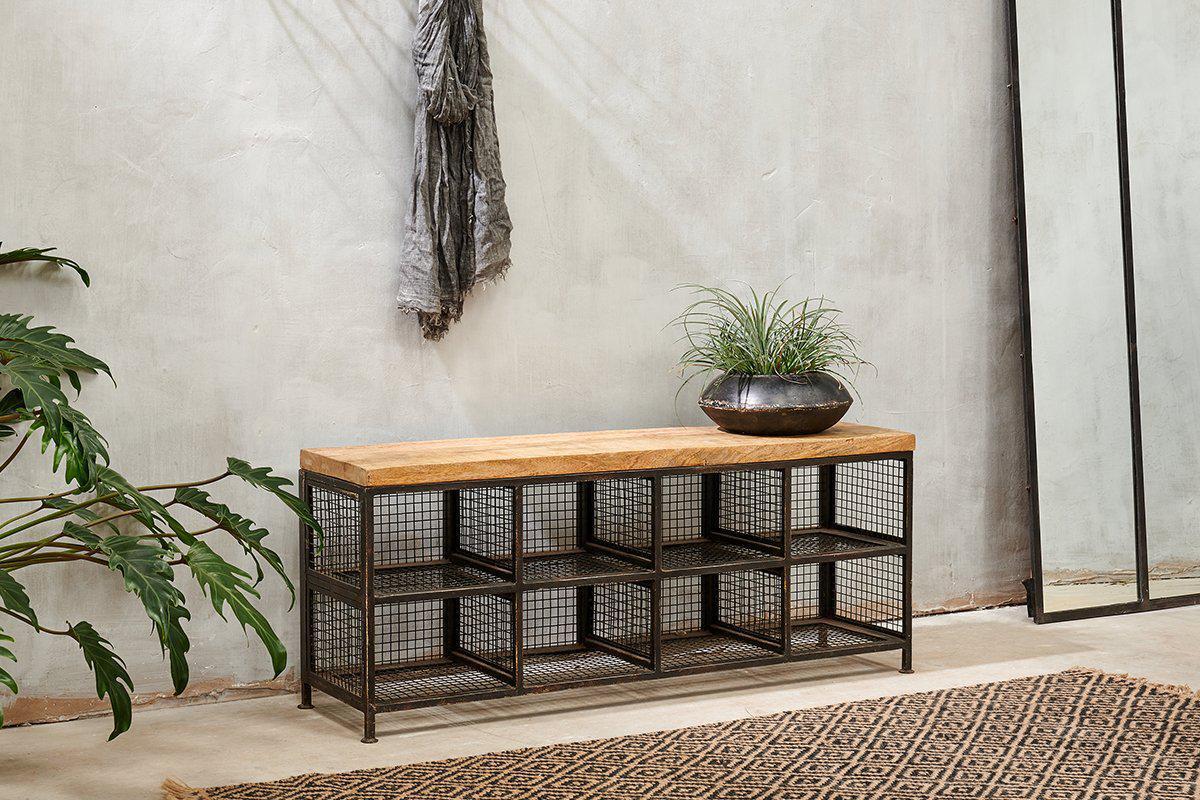The nkuku Hasa Industrial Storage Bench features a mango wood top and black metal wire mesh cubbies, perfect for hallway storage. Styled with a dark bowl planter, it suits grey walls, jute rugs, large plants, and mirrors.