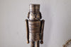 The Imay Nutcracker - Antique Brass by nkuku features a wooden soldier with a cylindrical hat, round eyes, and a mustache in a detailed uniform—ideal for festive styling or as part of your decorative nutcracker display.