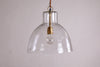 The Inayah Recycled Glass Pendant - Clear by nkuku features a wide, textured glass dome shade suspended by a chain, with a gold-toned socket visible inside, set against a plain, light background.
