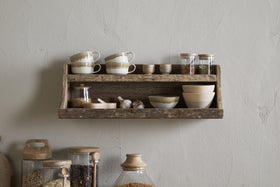 The nkuku Ibo Reclaimed Wood Storage Shelf - Natural displays cups, bowls, and jars on the wall, with larger glass jars below on the counter—all against a textured beige wall for stylish kitchen storage.