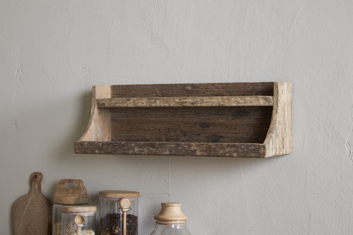 The nkuku Ibo Reclaimed Wood Storage Shelf - Natural adds rustic charm, mounted above a countertop with glass jars, a wooden cutting board, and a ceramic container—ideal for stylish kitchen storage.