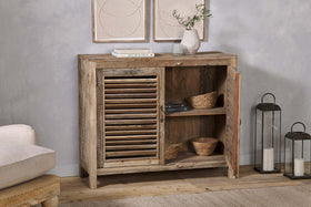 The nkuku Ibo Reclaimed Wooden Slatted Sideboard in natural features louvered doors and open shelving with baskets and bowls, topped with lanterns, framed art above, highlighting Indian artisan craftsmanship.