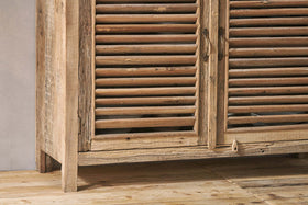 Close-up of the Ibo Reclaimed Wooden Slatted Sideboard by nkuku, featuring artisan-crafted louvered doors, weathered natural finish, ornate metal handles, and a small wooden latch accent on the lower panel.