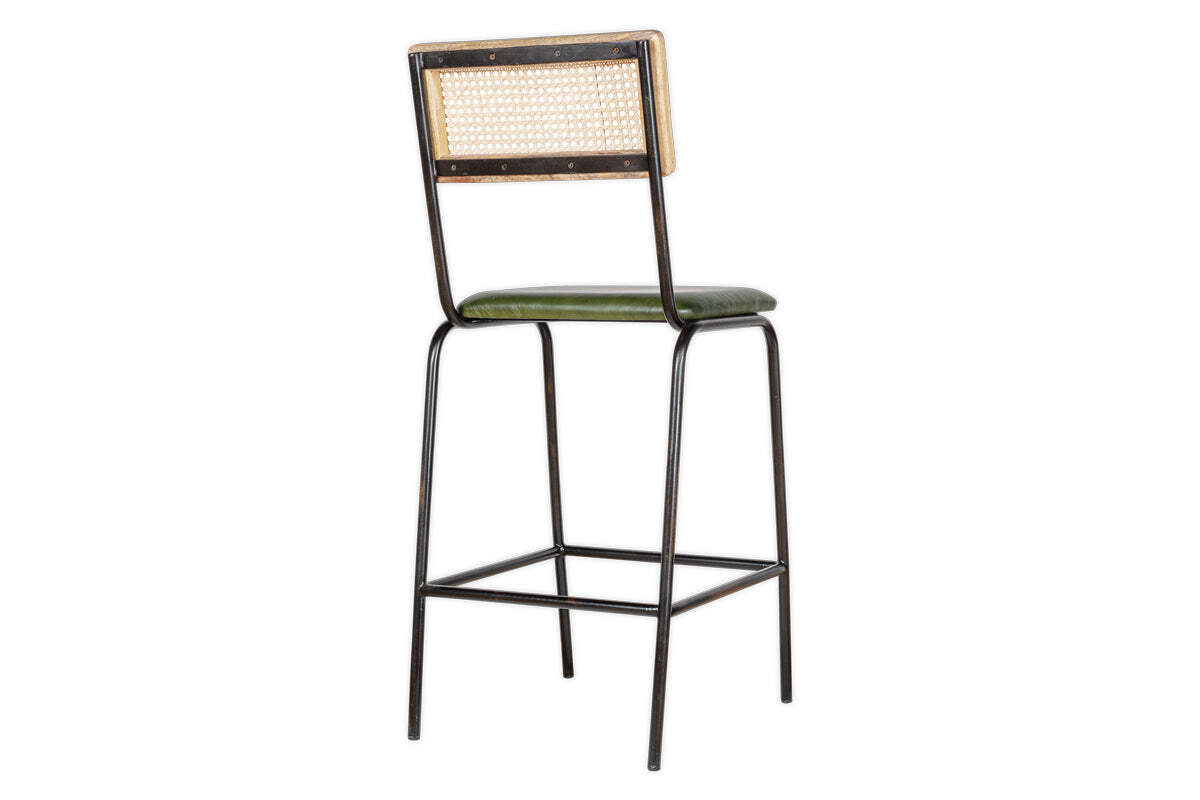The Iswa Leather & Cane Counter Chair by nkuku features a black metal frame, square woven cane back, and rich green leather seat. Slender legs with a footrest blend minimalist, industrial, and vintage styles for your kitchen island.
