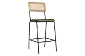The Iswa Leather & Cane Counter Chair by nkuku features a rich green upholstered seat, black metal legs with a footrest, and a woven cane back framed in light wood for a minimalist kitchen island look.