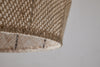 Close-up of the nkuku Jahari Woven Jute Pendant in Natural, featuring light brown jute fibers with a textured, mesh-like pattern against a plain light gray background—ideal for rustic home decor.