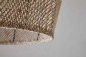 Close-up of the nkuku Jahari Woven Jute Pendant in Natural, featuring light brown jute fibers with a textured, mesh-like pattern against a plain light gray background—ideal for rustic home decor.