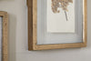 Close-up of the Jahala Wall Hung Photo Frame in antique brass by nkuku, featuring a textured finish and displaying artwork with dried flowers on white paper, hung on a light-colored wall.