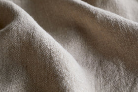 A close-up of the Junto Linen Tablecloth - Natural - Small by nkuku highlights its elegant weave and subtle linen texture.