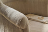 Close-up of the nkuku Kiana Cotton Armchair - Natural, featuring textured upholstery and a rounded armrest; on the seat are two stacked cream folders, one with a gold decorative clasp.