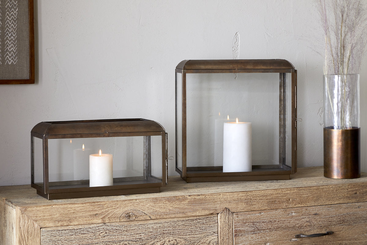 The Kiwanda Tall Lantern by nkuku in antique brass creates elegant candlelight decor, perfect for adding warmth and style to any space.