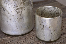 Two Kunjari Tealight Holders by nkuku in rustic gold with a weathered, speckled finish sit on a wooden surface—ideal for adding charm and classic rustic style to your space.