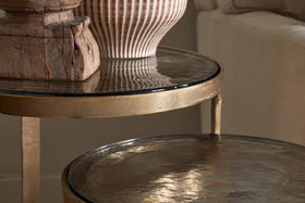 A close-up of nkukus Khidki Cast Metal & Glass Nesting Side Tables (Set of 2), showcasing hammered aluminium details and antique brass accents.