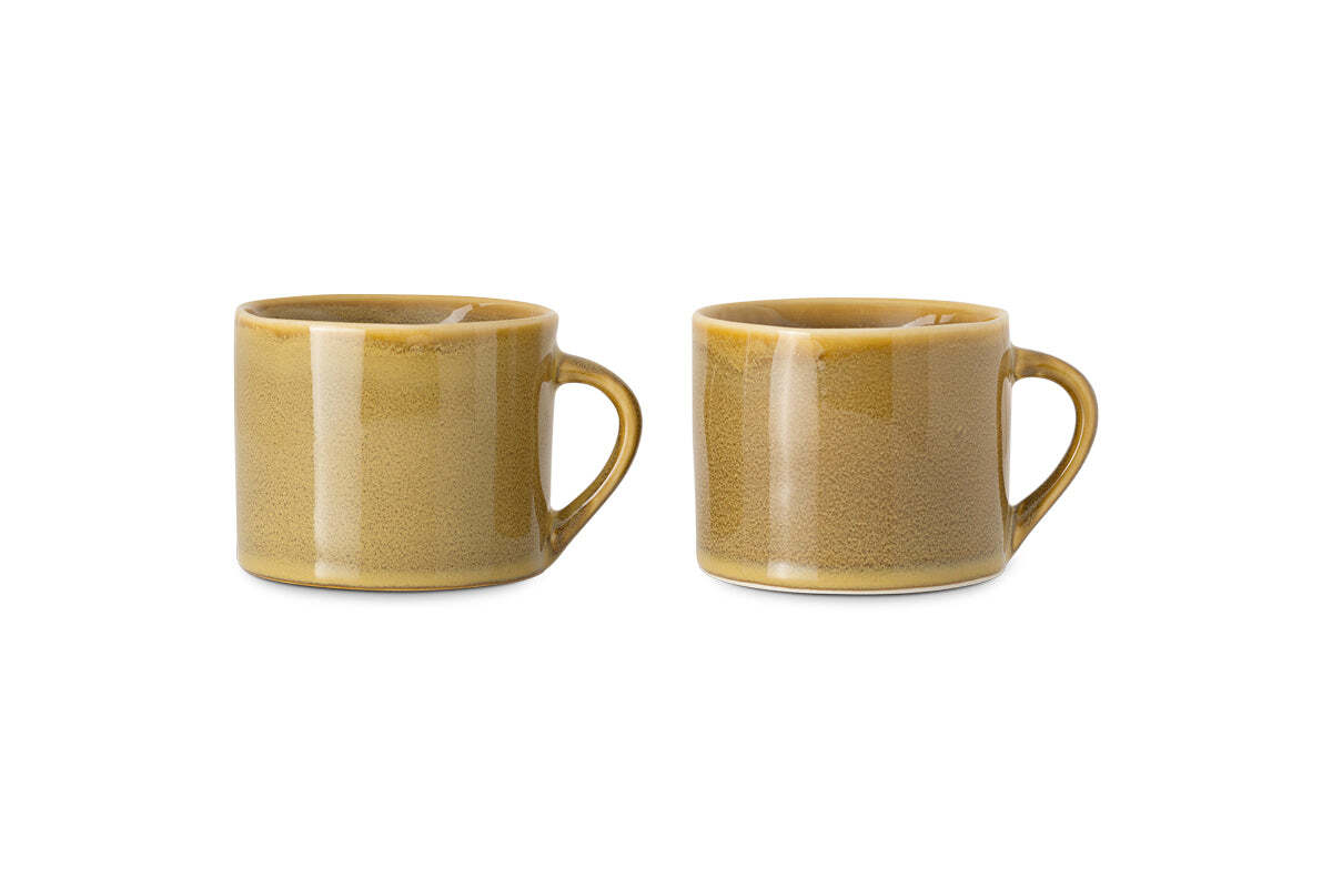 The nkuku Kalini Mugs - Green - Small (Set of 2) feature rounded bodies, large handles, and a glossy, slightly speckled finish. Shown side by side against a white background, these handmade mugs are beautifully crafted.