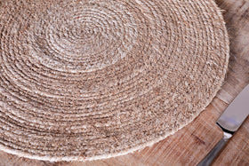 The Keso Woven Placemats by nkuku, made from natural banana fibre with a spiral design, add minimalist charm to your table. A silver knife peeks out in the corner, completing the look. Set includes 4 placemats.