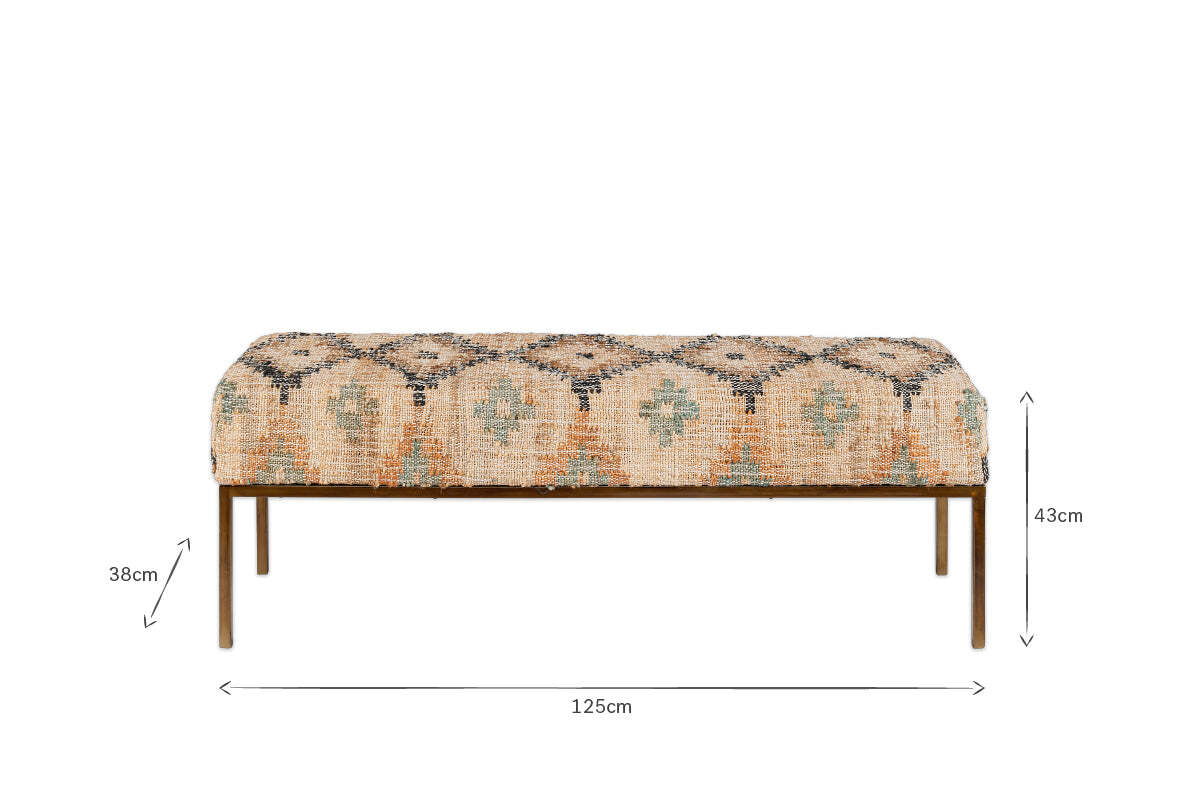 The Kesu Kilim & Iron Bench by nkuku features patterned beige and blue fabric, four slender iron legs, and measures 125cm wide, 38cm deep, and 43cm high. The front-facing image highlights its dimensions with measurement arrows.