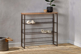 The nkuku Kiyoma Iron & Wood Tall Standing Shelves - Natural features three wire shelves and a mango wood top, perfect against a gray wall. A black plant pot, wooden bowl, woven basket, and round rug complete this organized entryway.