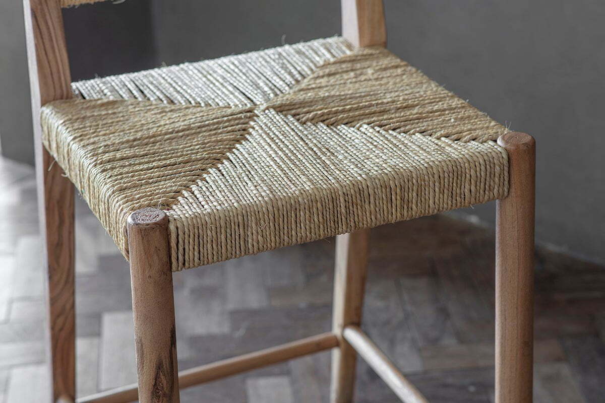 The nkuku Lohanda Acacia & Munja Grass Counter Chair features a handcrafted acacia frame and a seat intricately woven from natural beige munja grass, highlighting artisanal craftsmanship and elegant geometric patterns.