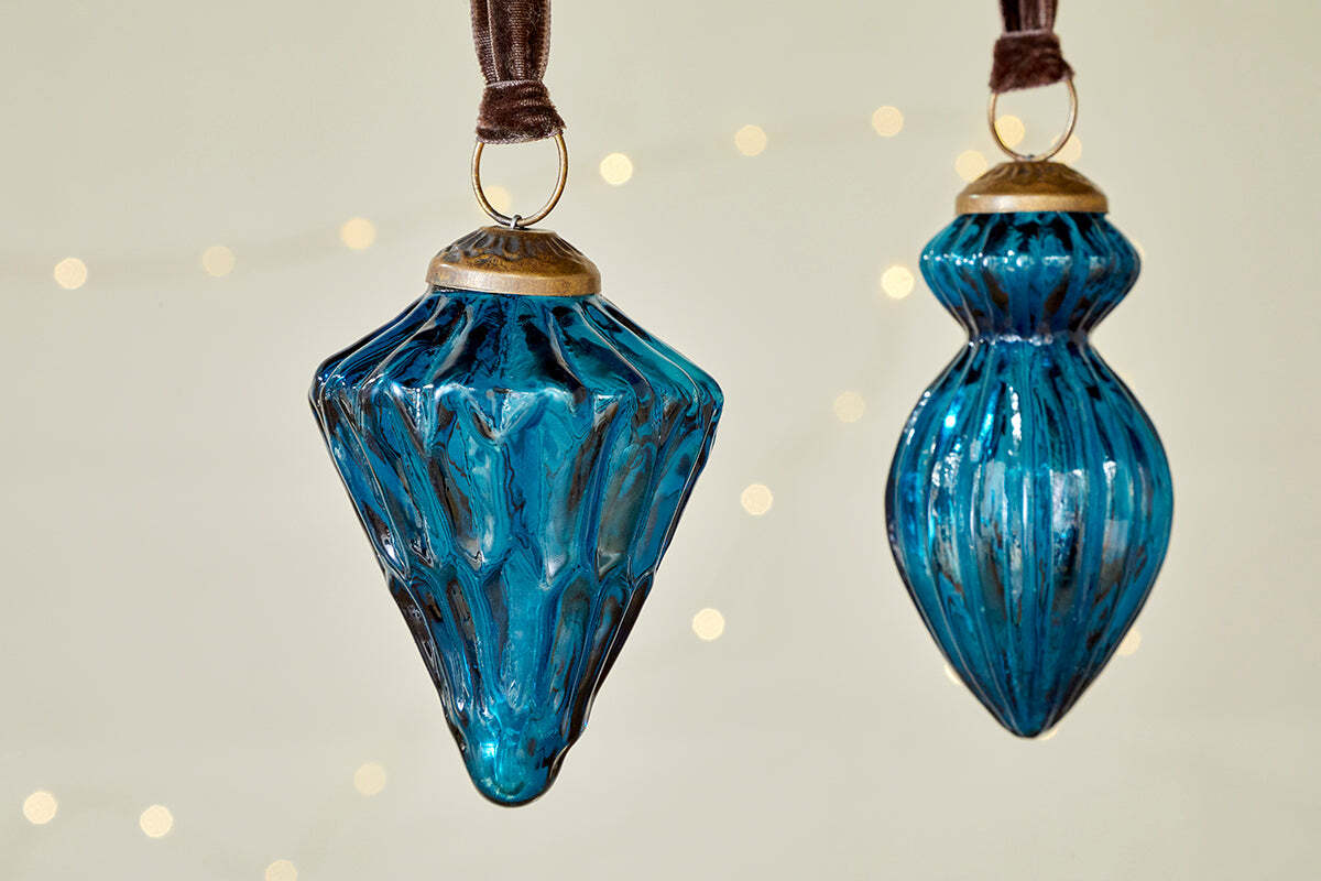 The nkuku Manipur Baubles - Indigo (Set of 3) feature elegant blue glass with gold accents and textured, geometric designs, hanging from brown ribbons—perfect vintage-style Christmas ornaments for festive decor.