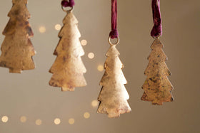 The nkuku Mishti Tree Baubles - Antique Brass (Set of 4, Small) feature a rustic gold finish and hang from maroon ribbons, creating a warm festive atmosphere with their antique charm.