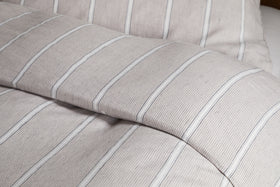 Close-up of a neatly made bed dressed in the Mora Hemp & Cotton Duvet Cover in Stone Grey by nkuku, showcasing soft, textured fabric for breathable comfort.