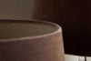 Close-up of two Mendai Velvet & Linen Lampshades in Mocha by nkuku, their smooth, velvety texture softly highlighted by gentle lighting against a blurred background.