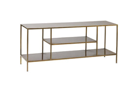 The nkuku Mahi Media Standing Shelf features a sleek, minimalist brass-finished metal frame and three open, dark-toned brass shelves—perfect for displaying entertainment equipment with modern style and open storage.