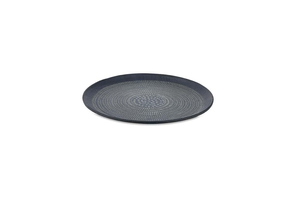 The Mahika Tray - Black by nkuku is a round, dark aluminum tray featuring a hand-etched dotted pattern in concentric circles, a raised rim, and a sleek black finish for a modern decorative touch. Photographed against a plain white background.
