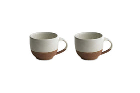 The nkuku Mali White and Terracotta mugs feature a minimalist design with an off-white glazed top and handmade terracotta base, combining rustic charm and modern style. Set of two mugs shown on a white background.