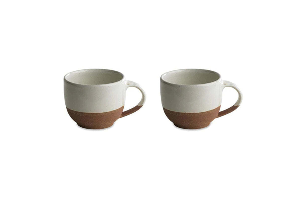 The nkuku Mali White and Terracotta mugs feature a minimalist design with an off-white glazed top and handmade terracotta base, combining rustic charm and modern style. Set of two mugs shown on a white background.