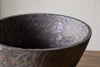 Close-up of the nkuku Nyati Wooden Serving Bowl, large size in dark brown, handcrafted with a textured finish and uneven rim, shown on a wooden surface against a light wall.