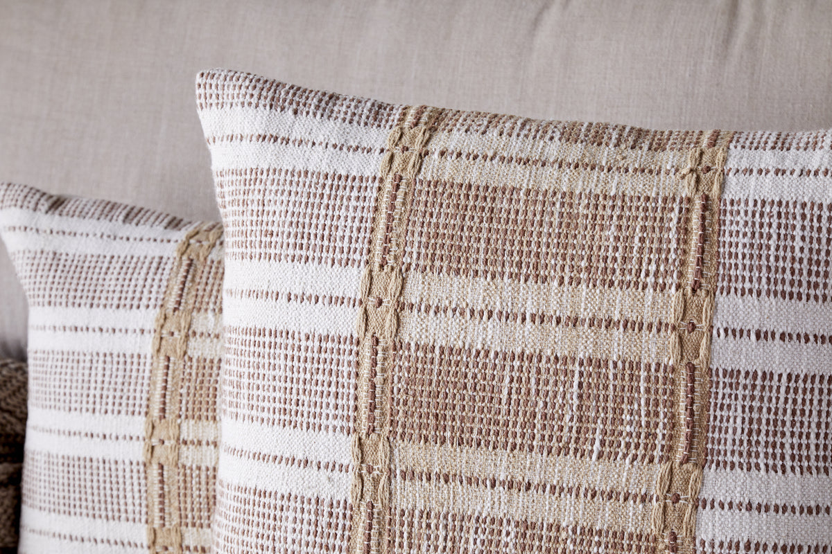 Two Nayika Cotton Cushion Covers by nkuku in a rust woven striped pattern add warmth and style to a light sofa—perfect decorative cushions with soft cotton covers.