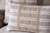 Two rectangular nkuku Nayika Cotton Cushion Covers in rust stripes are placed on a light fabric sofa. These textured, handmade-look covers add a cosy, inviting touch.