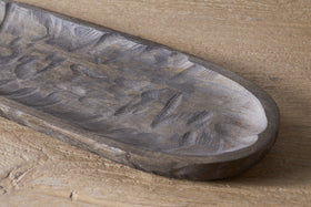 A close-up of the nkuku Nyati Serving Platter in dark brown, handcrafted from mango wood with textured grooves, resting on a light wooden surface—a stylish and sustainable home decor piece.